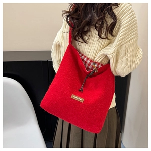 Detail view of red felt tote bag with check lining and drawstring closure in use