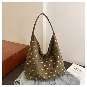Detail of dark olive suede hobo bag featuring polished gold metal studs on denim jacket