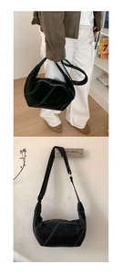 Close-up of black suede hobo bag featuring contrasting white stitching and geometric design