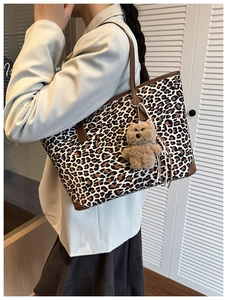 Detail of leopard print tote bag with brown leather trim and cute plush bear charm