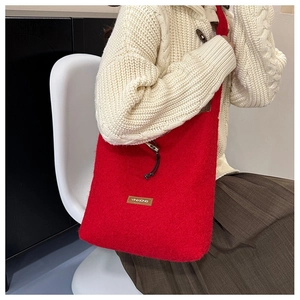 Close-up of red wool tote bag with drawstring closure and leather logo patch