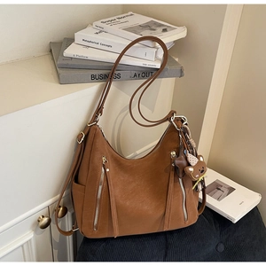 Détail du sac hobo marron vintage avec fermetures éclair et pendentif ours mignon