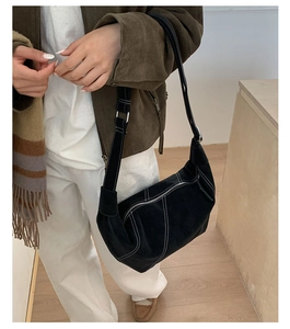 Detail of vintage black suede hobo bag featuring decorative white contrast stitching