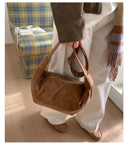Detail of vintage brown suede dumpling bag with contrast stitching and knotted strap