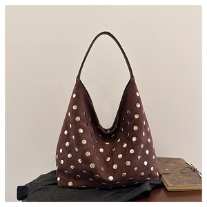 Detail of vintage brown suede hobo bag featuring decorative golden metal rivets