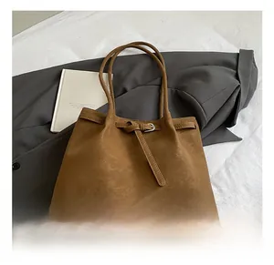 Close-up of brown matte tote bag featuring minimalist leather strap and buckle detail