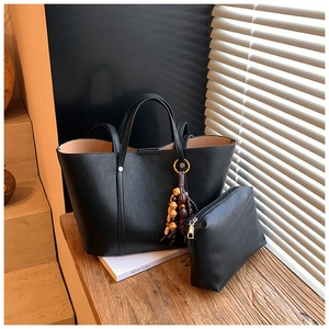 Dettaglio del set borsa tote nera con pochette coordinata e ciondolo nappa in legno