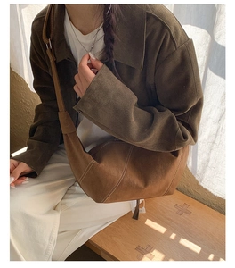 Brown suede crescent bag with white contrast stitching in a cozy lifestyle setting