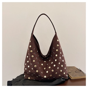 Close-up of vintage dark brown tote bag with gold rivet studs on suede texture