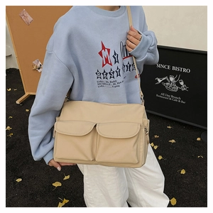 Outdoor street style shot of a cream-colored nylon crossbody bag with dual front pockets