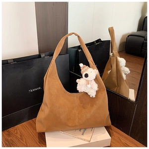 Detail of caramel brown suede tote bag featuring a cute plush bear charm on the handle