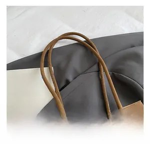 Detail view of the brown suede tote bag featuring a leather handle and metal buckle strap