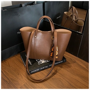 Dettaglio della borsa tote in pelle marrone con pendente in perline di legno