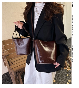 Detail of dark brown polished leather bucket bags with Lucky Bag embossed text and strap