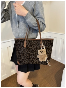 Detail of leopard print tote bag with brown handles and a cute plush bear charm
