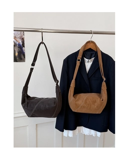 Detail view of crescent shoulder bags with contrast stitching in coffee and caramel leather