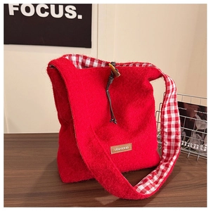 Detailed view of red plush tote bag with wooden horn buckle and plaid fabric lining