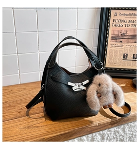 Detail of black lychee grain leather bucket bag with a cute plush rabbit pendant charm
