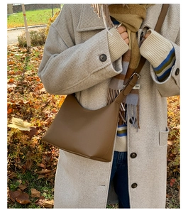 Detail of lychee pattern brown leather bucket bag with silver metal buckle and strap