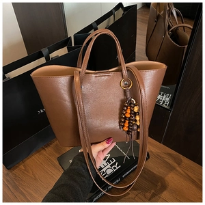Dettaglio della borsa tote vintage marrone con ciondolo a nappe di perline e due manici