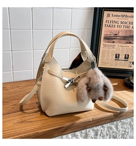 Macro detail of creamy lychee leather texture and silver buckle on bucket bag