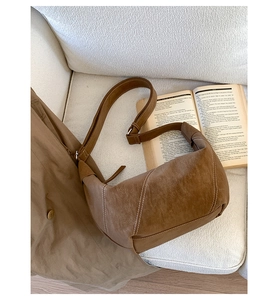 Detail of vintage brown crescent bag with contrast white stitching on fabric sofa