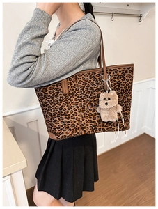 Detail of leopard print tote bag with brown leather trim and cute plush bear charm