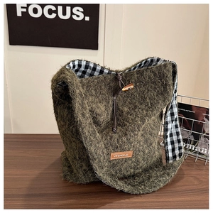 Close-up of moss green plush tote bag featuring a toggle closure and checkered lining