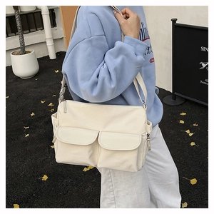 Close-up of off-white nylon crossbody bag featuring double pockets and adjustable strap