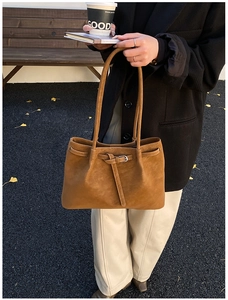 Detail view of a vintage brown leather tote bag featuring a knotted belt with silver buckle