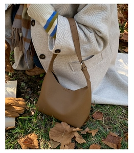 Detail of vintage brown pebble leather bucket bag on an autumn leaves background