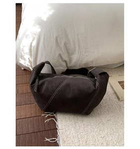 Detail of dark leather crescent bag with white contrast stitching and knotted handle