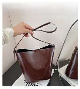 Detailed close-up of dark brown leather bucket bag showing smooth texture and bottom logo