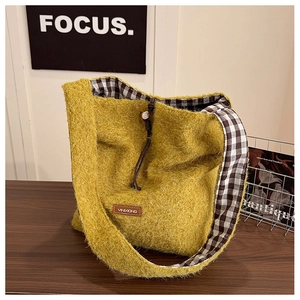Close-up of yellow fuzzy wool tote bag featuring brown leather tag and checkered lining