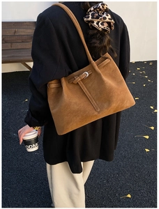 Close-up of vintage brown leather tote bag with metal buckle on autumn leaves