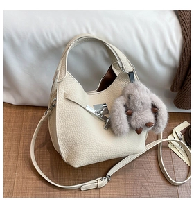 Detail of cream leather bucket bag with pebble texture, silver twist lock and bunny charm