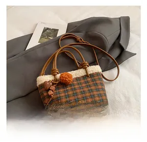 Detailed view of plaid bucket bag with faux fur trim and decorative heart beads charm