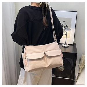 Detail of adjustable strap and dual front flap pockets on beige nylon crossbody bag