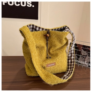 Detail of yellow plush bucket bag with horn button closure and checkered cotton lining