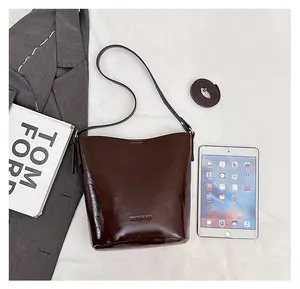 Detail view of a vintage dark brown bucket bag showing polished texture and size with an iPad