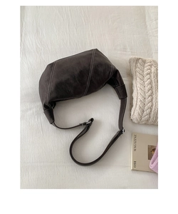 Detail of dark brown crescent bag with white contrast stitching and adjustable strap