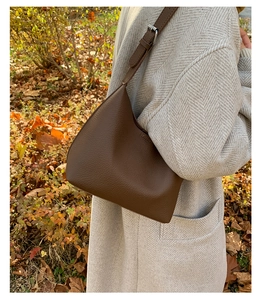 Detail of dark brown lychee leather hobo bag worn with a grey winter coat