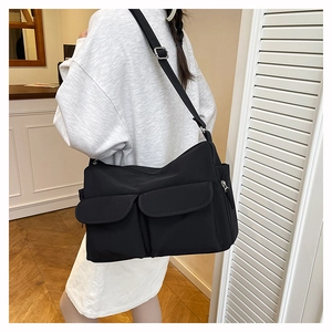 Minimalist black nylon crossbody bag featuring double front flap pockets and adjustable strap