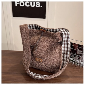 Detail of fuzzy brown tote bag featuring toggle closure and plaid lining on wooden table