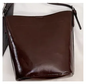 Detail of deep brown bucket bag showing glossy leather texture and dual stitching seams