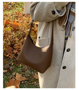 Detail of a brown lychee pattern leather hobo bag worn with an autumn wool coat