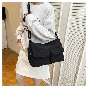 Detail of black nylon crossbody bag with double front flap pockets and adjustable strap