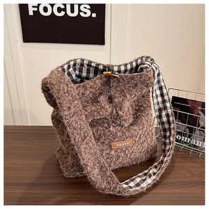 Detail of wool tote bag showing fuzzy brown texture with horn buckle and plaid lining