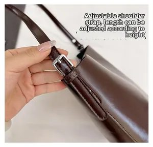 Close-up of adjustable strap with silver buckle on a dark brown glossy leather bag