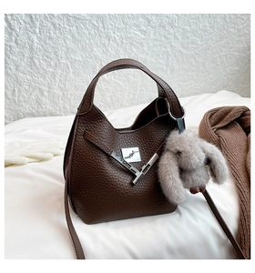 Detail of dark brown pebble leather bucket bag with silver twist lock and rabbit charm